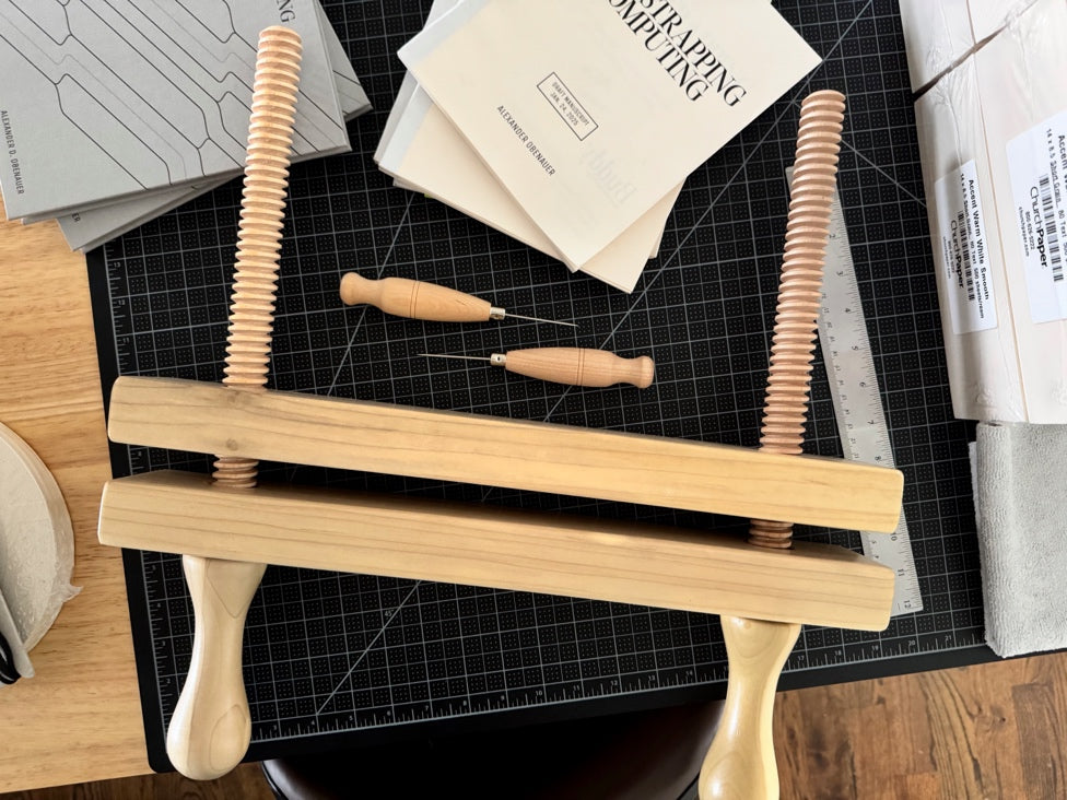 Finishing press and bookbinder's awls near draft manuscript