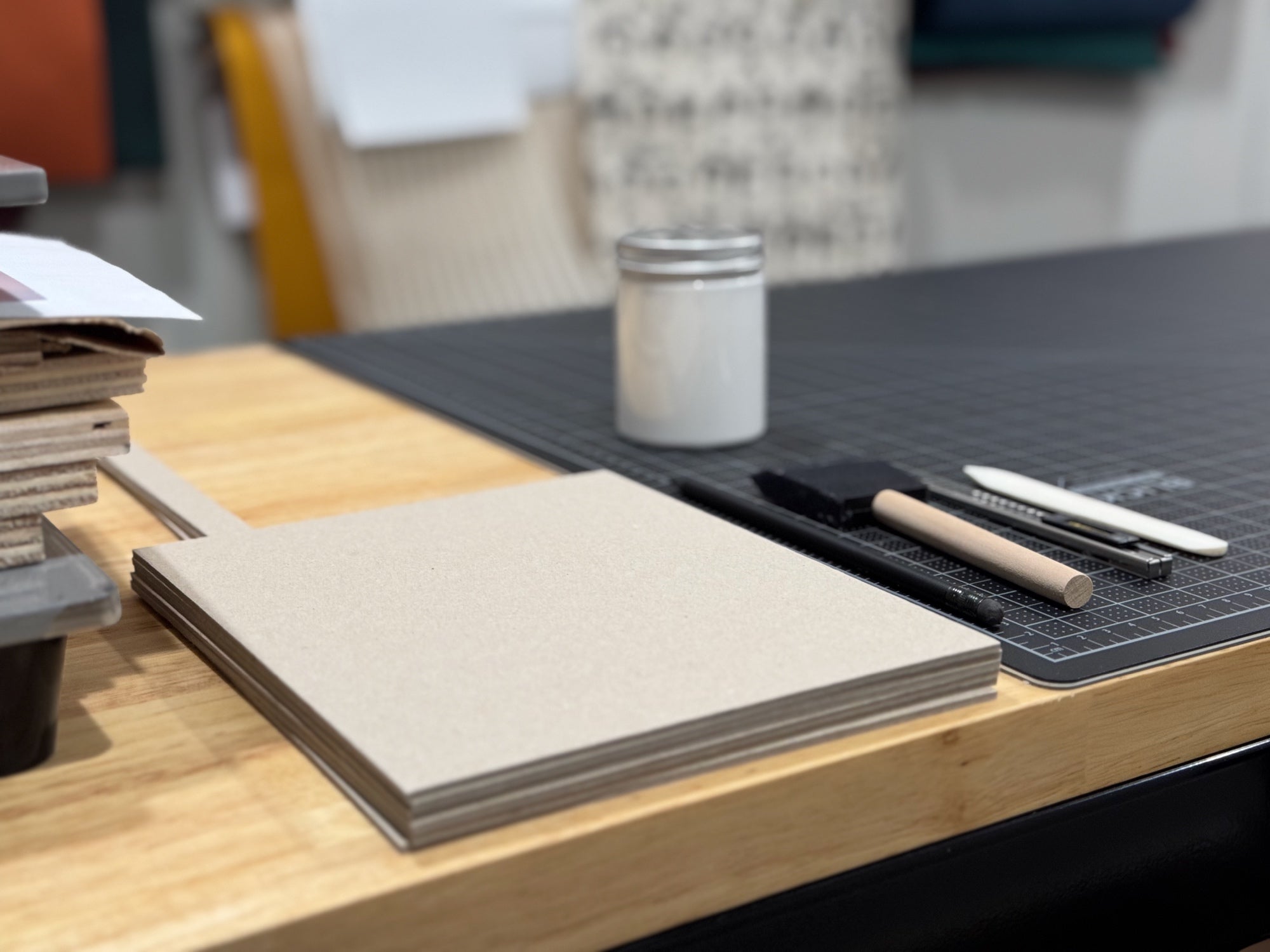 Bookbinding materials and tools on the workbench next to the cutting mat